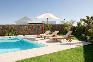 una piscina con due sedie a sdraio e un ombrellone e una piscina di Beautiful Villa Ambar a Puerto del Carmen
