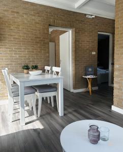 uma mesa branca e cadeiras num quarto com uma parede de tijolos em -Casa Nova- nabij het meer, duinen en restaurants em Noordwijkerhout