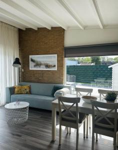 een woonkamer met een blauwe bank en tafels bij -Casa Nova- nabij het meer, duinen en restaurants in Noordwijkerhout