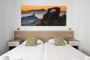 a bedroom with a bed with a painting on the wall at Canteras Suites in Las Palmas de Gran Canaria