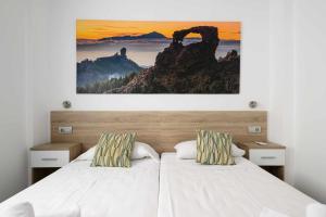ラスパルマス・デ・グランカナリアにあるCanteras Suitesの壁に絵が飾られたベッドのある寝室