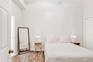 a white bedroom with a bed and a mirror at Stars on State in the Heart of Downtown in Mobile