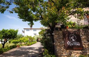 un muro di pietra con un cartello di fronte a un edificio di La casa del Maestro a Pisciotta