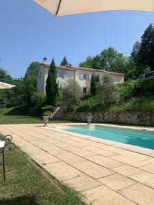 a swimming pool in a yard with a house in the background at Villa la bastide piscine et jacuzzi in Silhac