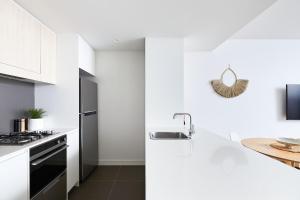 a white kitchen with a sink and a stove at The Swell in Newcastle