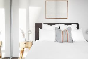a white bedroom with a bed with white sheets and pillows at The Swell in Newcastle