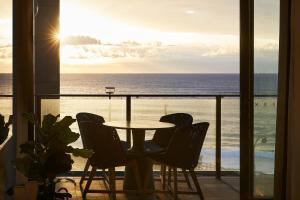 einen Tisch und Stühle auf einem Balkon mit Meerblick in der Unterkunft The Swell in Newcastle