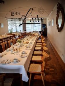 a long table in a restaurant with white tables and chairs at Hotel zu den Linden in Wachtberg