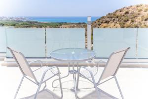 einen Glastisch und Stühle auf einem Balkon mit Aussicht in der Unterkunft Villa Aqua Queen in Coral Bay