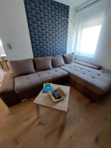 a living room with a brown couch and a table at Pintyőke Vendégház Tőserdő in Lakitelek