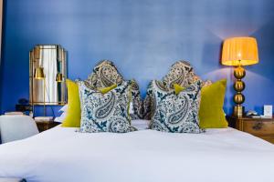 Dormitorio azul con cama blanca y almohadas en La Fontaine Boutique Hotel by The Oyster Collection, en Franschhoek