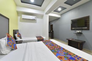 a hotel room with two beds and a flat screen tv at HOTEL GOLD LEAF in Ahmedabad