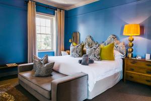 a blue bedroom with a large bed and a window at La Fontaine Boutique Hotel by The Oyster Collection in Franschhoek