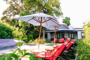 a group of red chairs and an umbrella at La Fontaine Boutique Hotel by The Oyster Collection in Franschhoek