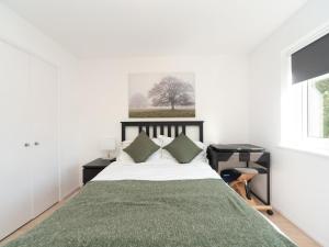 een witte slaapkamer met een bed met een groene deken bij Pass the Keys Chic apartment amazing location in Teddington