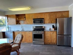una cocina con armarios de madera y electrodomésticos de acero inoxidable en River house, en Campbell River
