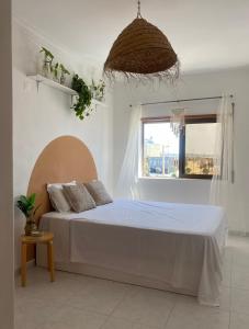 a bed in a white room with a window at Apartamento Vista Praia e Mar- Costa da Caparica in Costa da Caparica