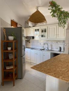 a kitchen with white cabinets and a sink and a refrigerator at Apartamento Vista Praia e Mar- Costa da Caparica in Costa da Caparica