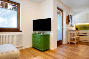 een slaapkamer met een groene dressoir en een flatscreen-tv bij La casa di Marco in Cavalese