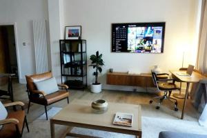 a living room with chairs and a table and a tv at Stylish city-centre apartment with balcony in Liverpool