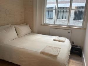 ein weißes Bett in einem Zimmer mit Fenster in der Unterkunft Stylish city-centre apartment with balcony in Liverpool