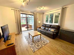 a living room with a leather couch and a table at Large 5 bed detached house near Stansted Airport in Stansted Mountfitchet