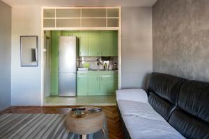 a living room with a couch and a kitchen with green cabinets at Apartman Centar in Niš