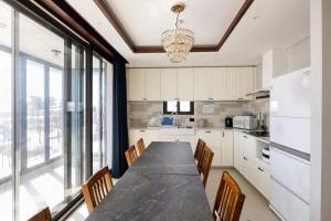 a kitchen with a long table with chairs and a large window at Miracle Suite house 201 pool villa in Incheon