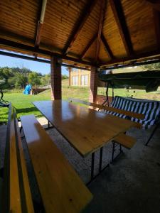 a wooden picnic table in a pavilion with two benches at Vikendica Brvnara Marčetić in Banja Luka