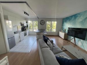 a living room with a couch and a kitchen at Disney appartement in Chessy