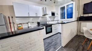 uma cozinha com armários brancos e bancadas pretas em Appartement moderne cosy et Calme - 15 min Paris em Chilly-Mazarin