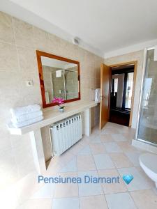 La salle de bains est pourvue d'un lavabo et d'un miroir. dans l'établissement Pensiunea Diamant, à Ghimbav