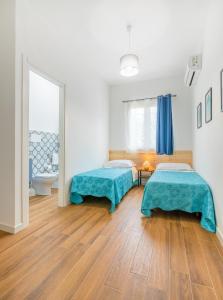 two beds in a room with wooden floors at Arricàmpati Rooms in Villa & RENT CAR Airport in Carini