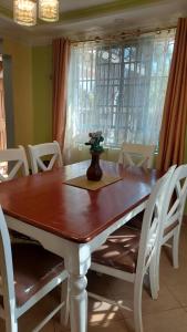een eettafel met witte stoelen en een vaas erop bij Nina's Home in Hoeys Bridge