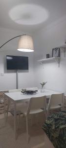 uma mesa de jantar branca com cadeiras e uma televisão em Casa da Tia Binda em Monção
