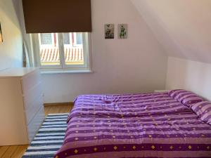 - un lit violet dans une chambre avec fenêtre dans l'établissement Fewo Urlaubsspaß, à Kalyves