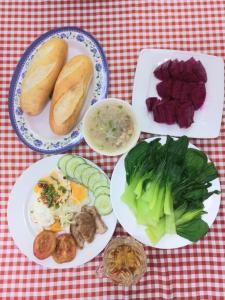 einen Tisch mit Teller mit Lebensmitteln auf einem roten und weißen Tischtuch in der Unterkunft Thăng Long Hotel in Dong Hoi