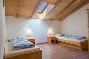 two beds in a room with wooden floors and a window at Mongaduierhof Apt Schlern in Fie allo Sciliar