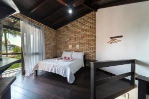 a bedroom with a bed and a brick wall at Pousada Albacora in Bombinhas +52 photos