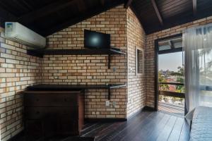 a room with a brick wall with a tv on the wall at Pousada Albacora in Bombinhas