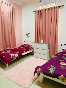 een slaapkamer met 2 bedden en roze gordijnen bij Homestay AAA Bukit Keluang Besut Terengganu in Kampung Raja