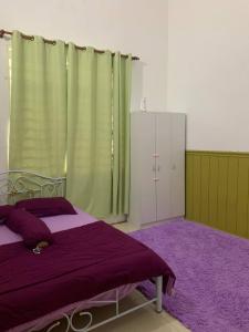 een slaapkamer met een bed en een paars tapijt bij Homestay AAA Bukit Keluang Besut Terengganu in Kampung Raja