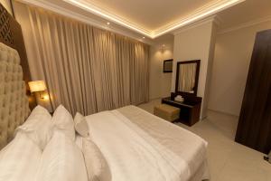 1 dormitorio con 1 cama blanca grande y espejo en Burj Al Hayat Furnished Suites - Al Malaz, en Riad