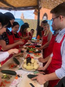 un grupo de personas de pie alrededor de una mesa con comida en Riad Layla Rouge, en Marrakech