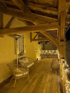 a porch with chairs and lights on a wooden floor at 300m2 cadre idyllique - 4 chambres - 6pers. in Mareuil-sur-Belle