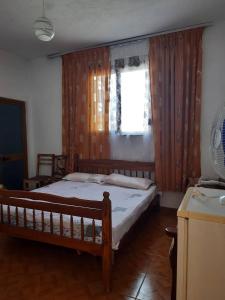 a bedroom with a bed and a window with curtains at The quiet house in Durrës