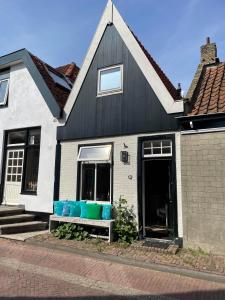 uma casa a preto e branco com um banco com almofadas azuis em Het Heertje em Den Hoorn