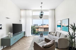 a living room with a couch and a tv at Sunsets Paradise 2BR with Private Parking in Herzelia 