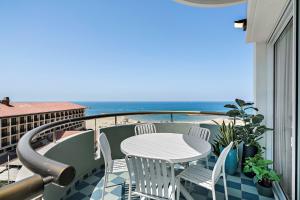 balcón con mesa, sillas y vistas al océano en Sunsets Paradise 2BR with Private Parking, en Herzelia 