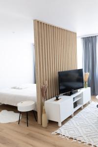 um quarto com uma cama e uma televisão num armário branco em Apartament Pastel Room em Leśna